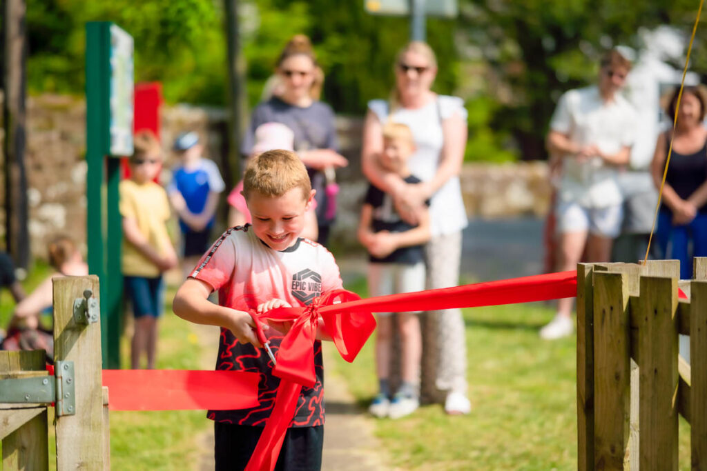 Little boy cuts a ribbon to open the play park
