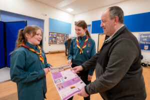 Community Partnership Chair Andy Pratt and two scouts look at one of the designs which they are holding