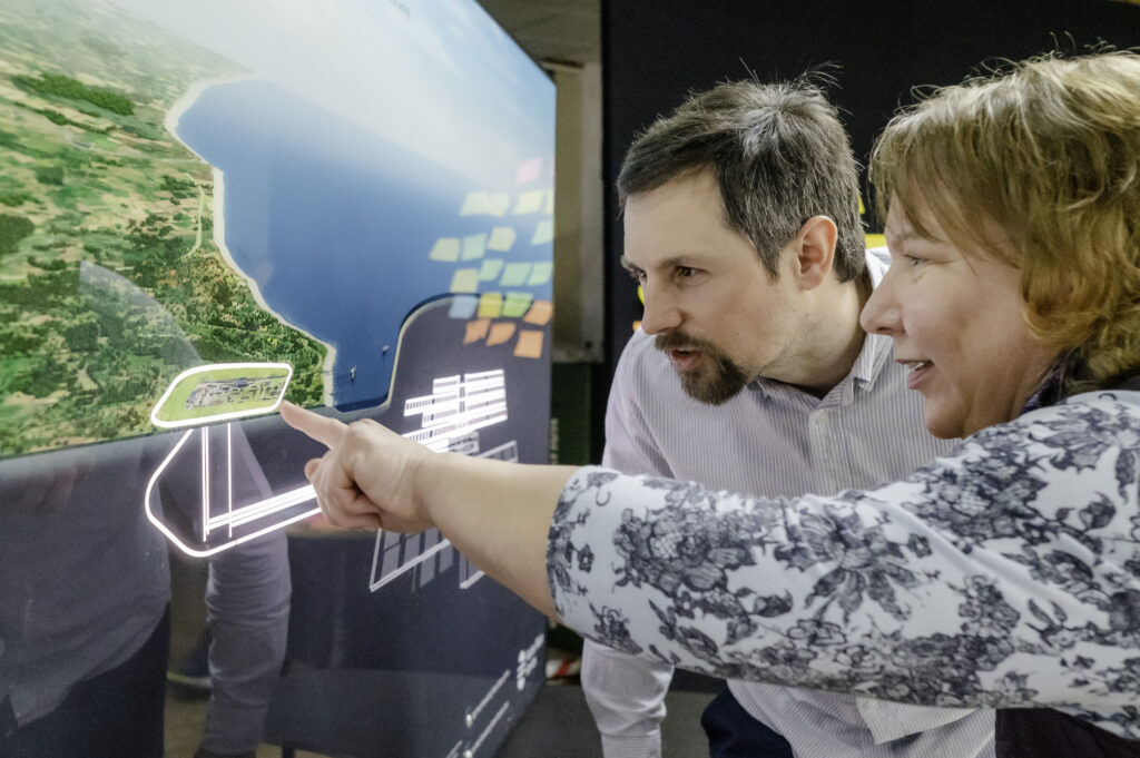 Man and Woman talking and looking at a map on screen
