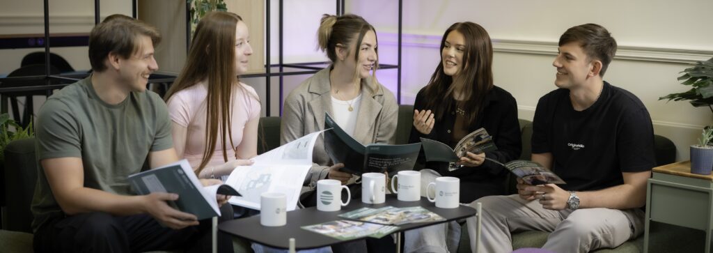 Five young people sitting down, chatting around a table