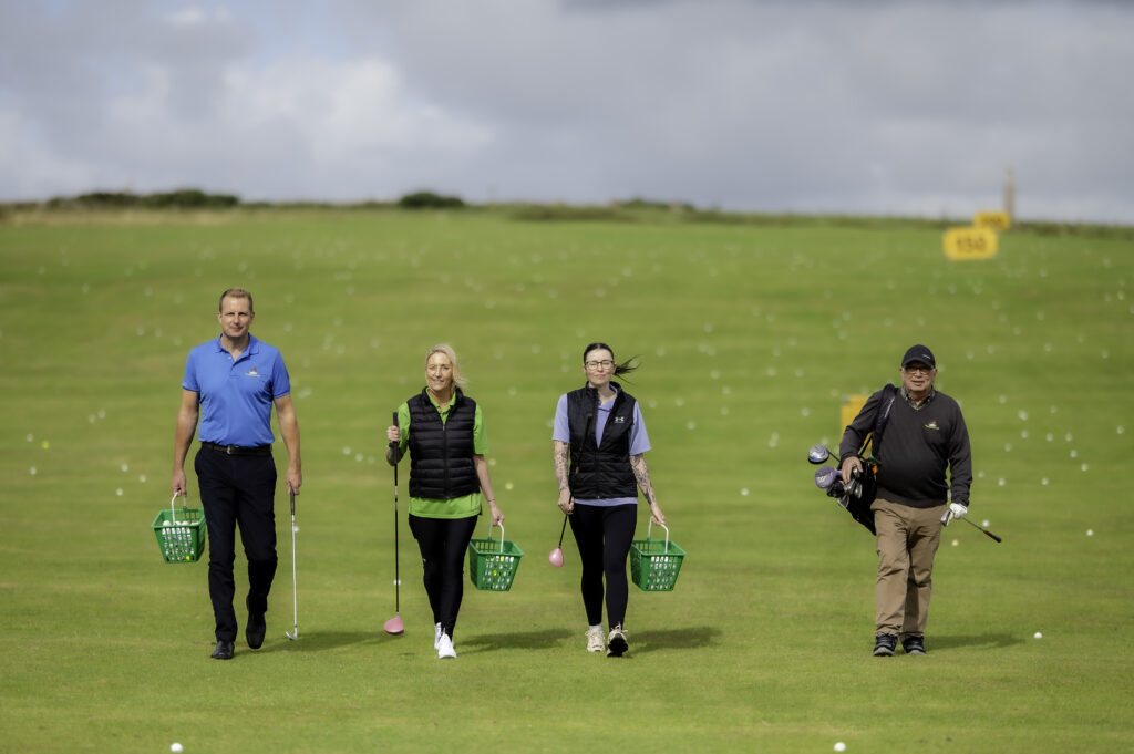 Four people on a golf course walking towards the camera
