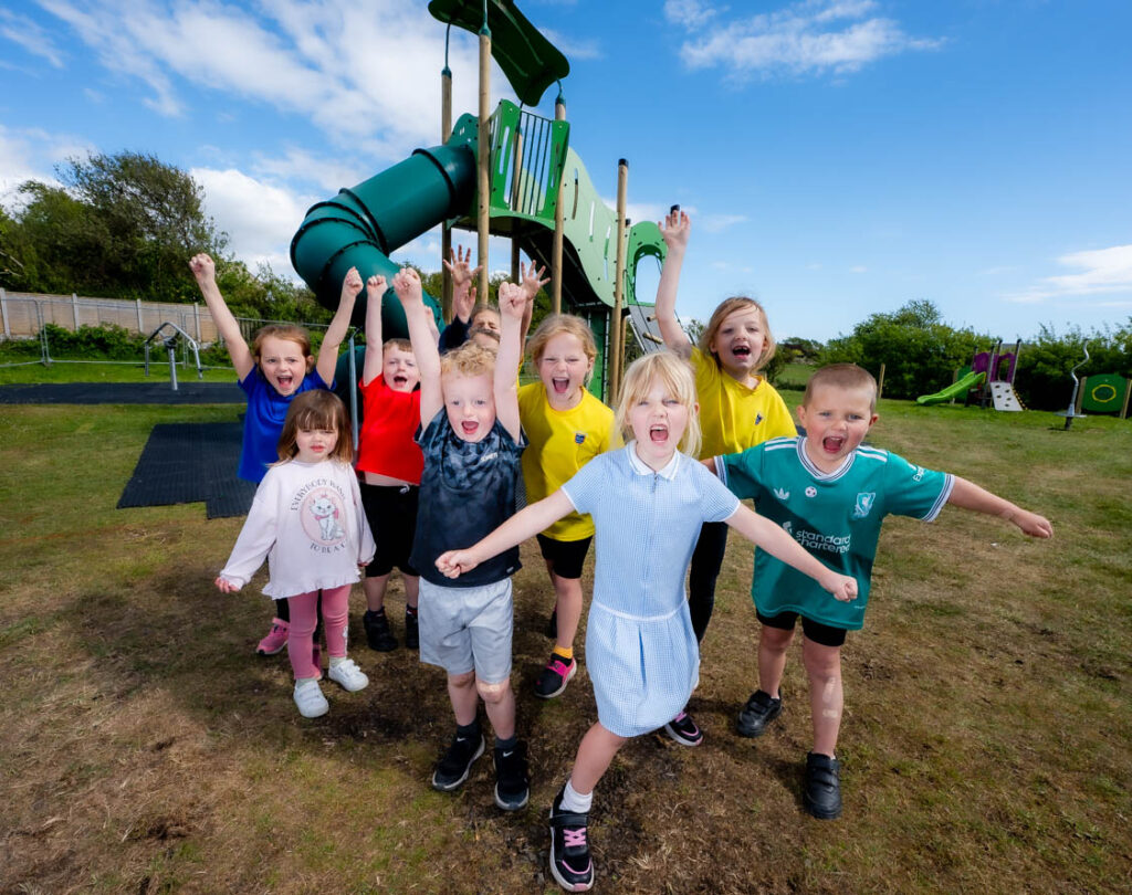 A group of young children in front of some outdoor play equipment